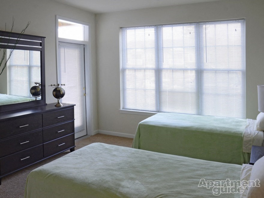 a bedroom with two beds and a dresser and a window