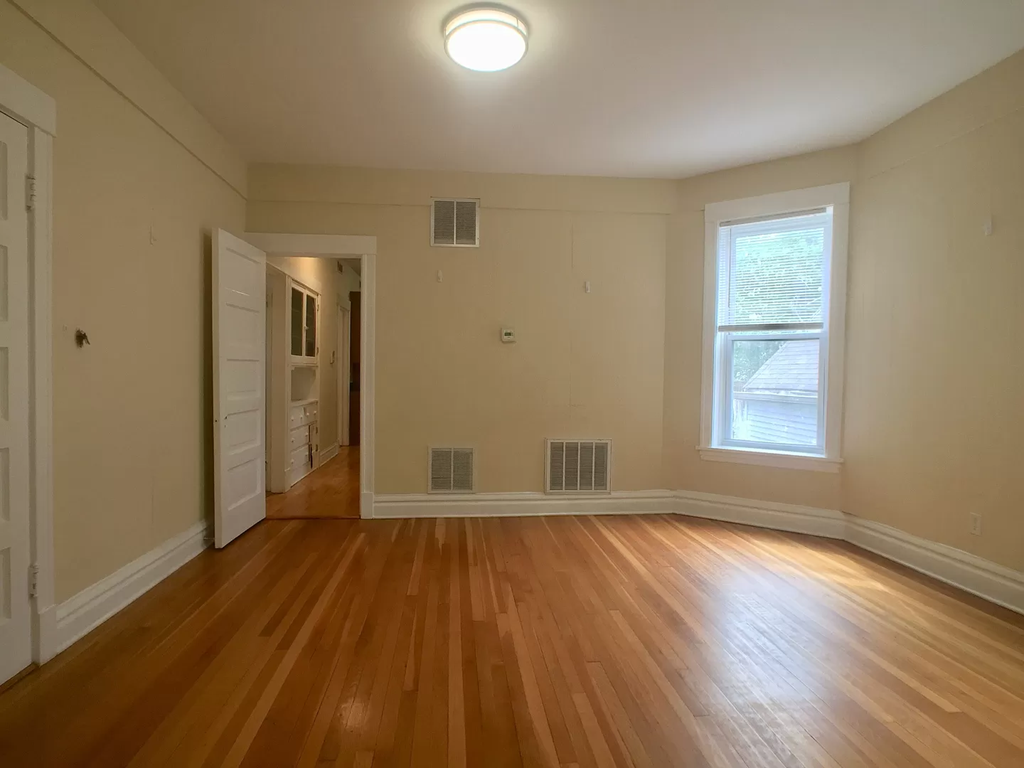 an empty living room with wooden floors and a window