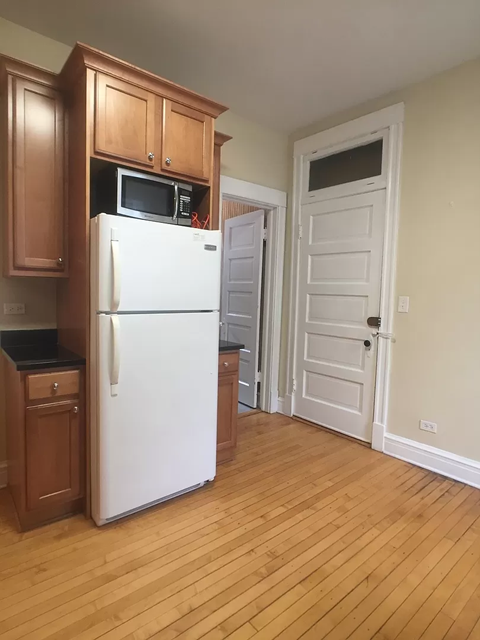 a kitchen with a white refrigerator and wooden floors