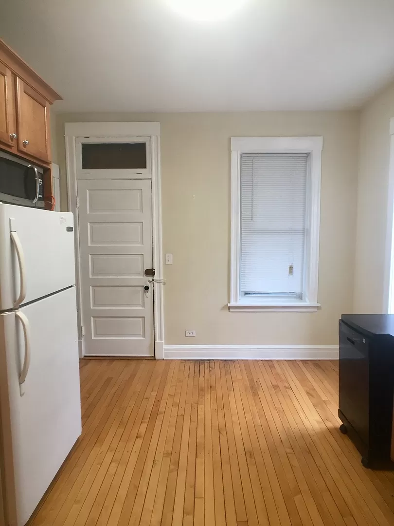 an empty kitchen with a wooden floor and a white door