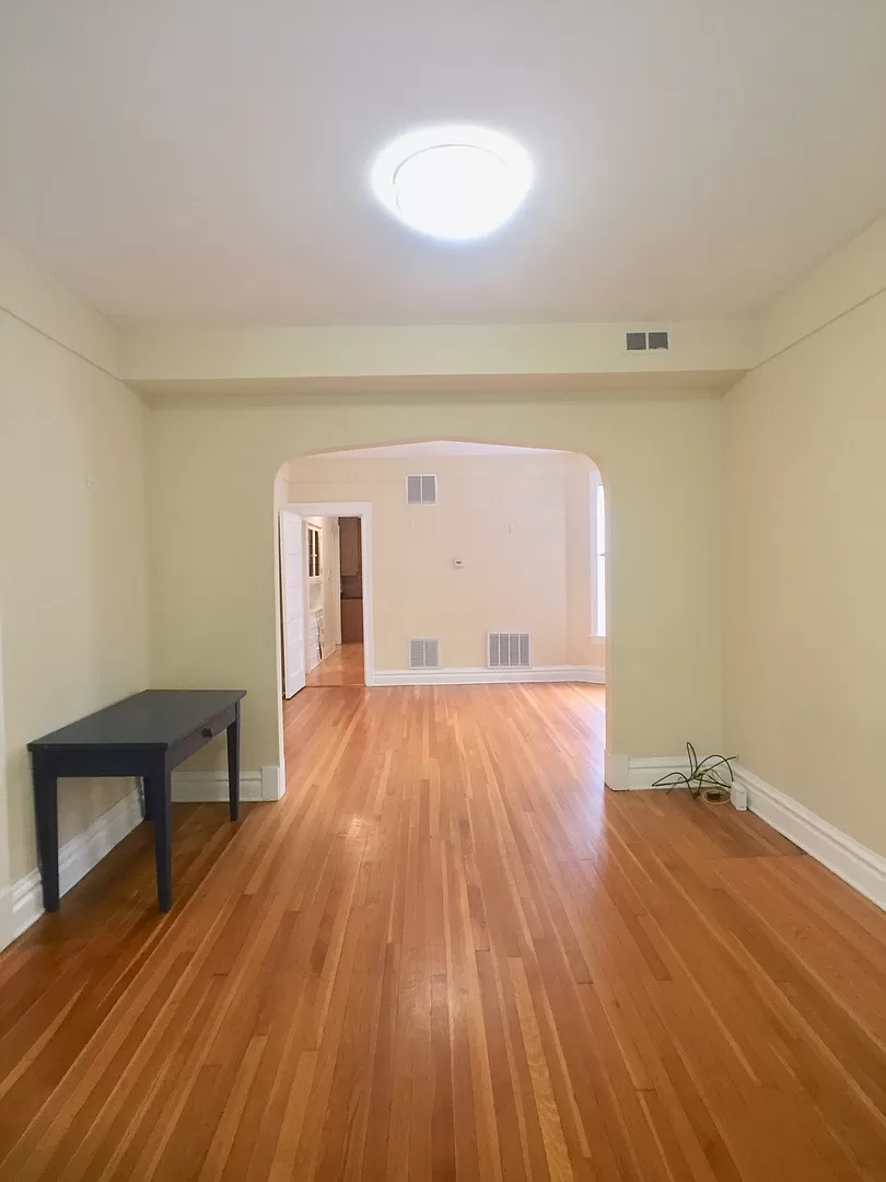an empty living room with a hard wood floor and a black table