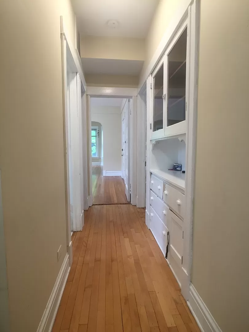a hallway with a wooden floor and a white cabinet