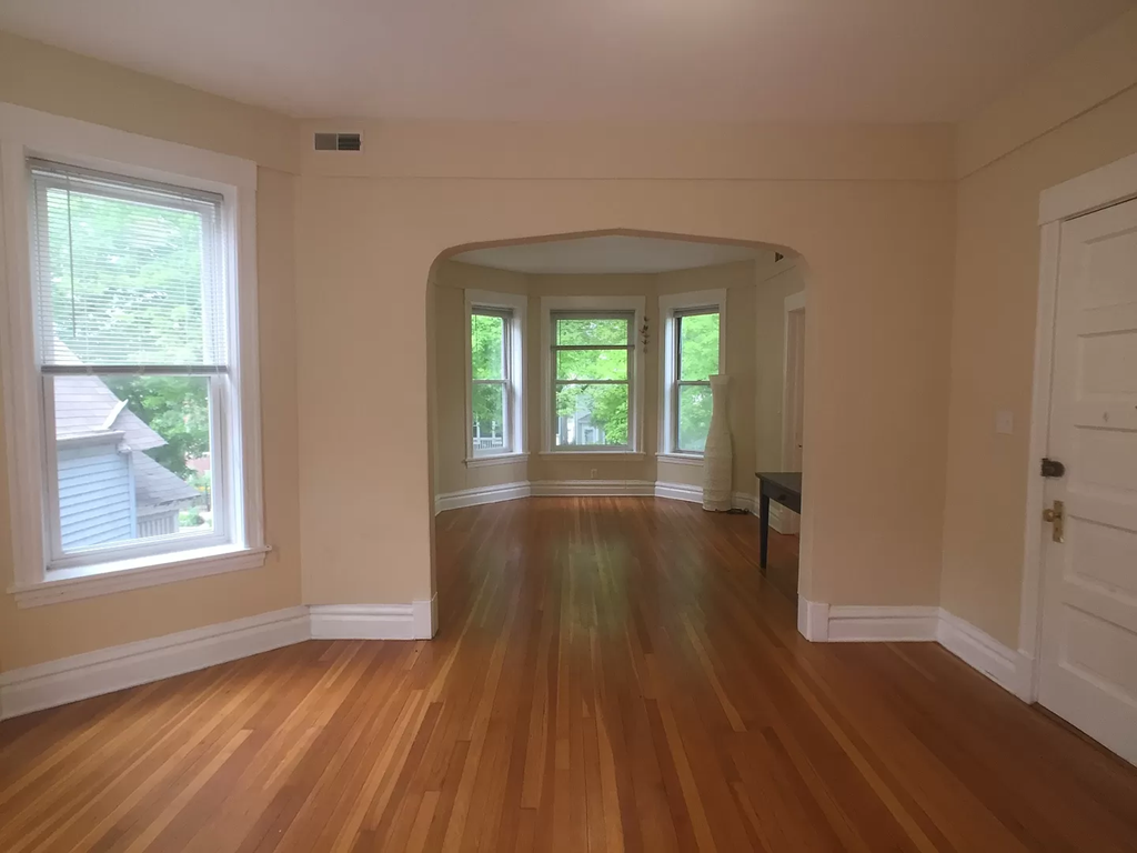 an empty living room with a hard wood floor and windows