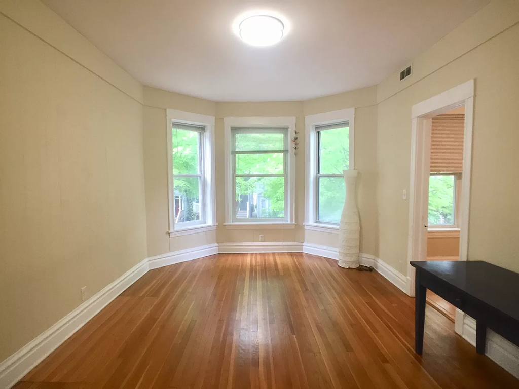 an empty living room with a hard wood floor and windows