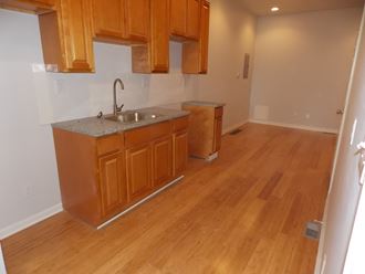 an empty kitchen with wooden floors and wooden cabinets and a sink