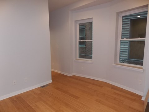 an empty room with wooden floors and two windows