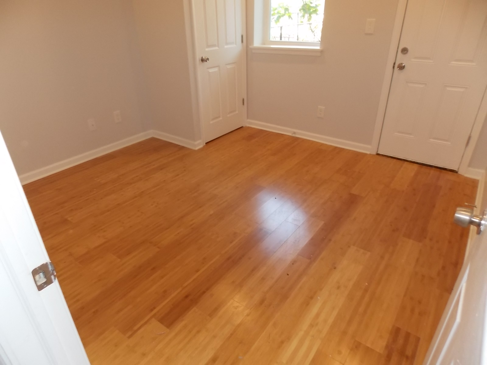 an empty living room with wooden floors and white doors