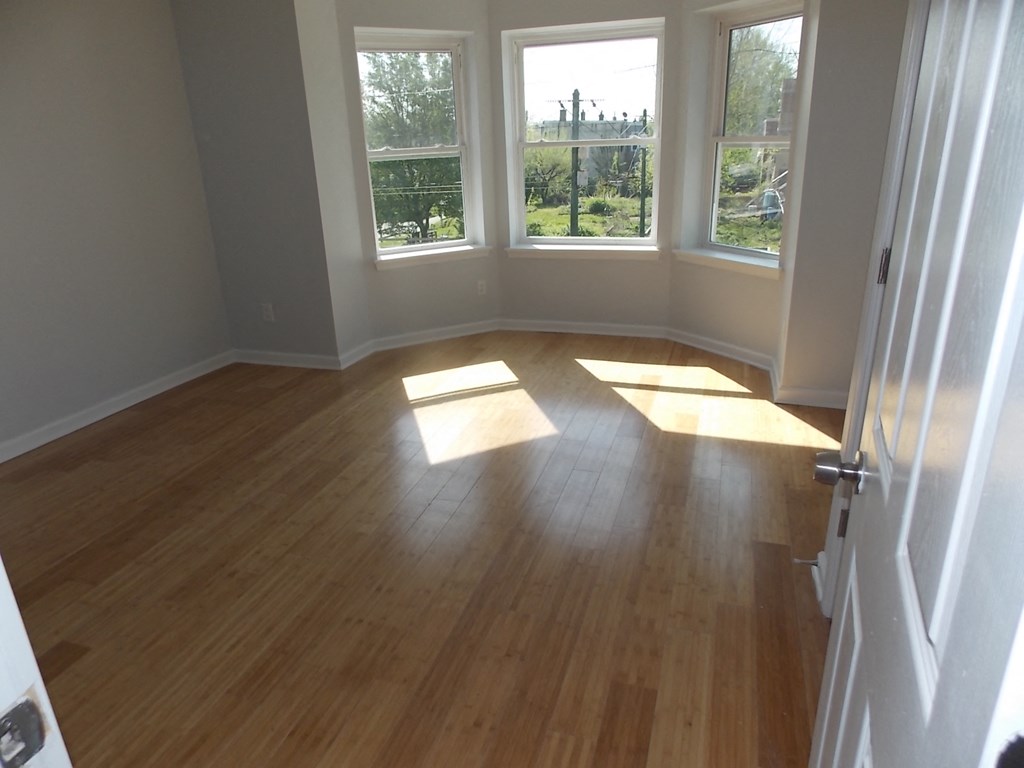 an empty living room with wooden floors and windows