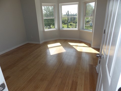 an empty living room with wooden floors and windows