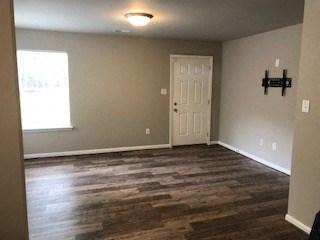 an empty living room with a white door and wood floors