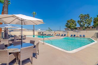 Pool area with lounge furniture and umbrellas at Serrano Apartments, California