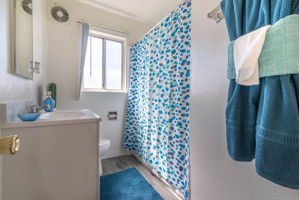 bathroom with colorful shower curtain over tub shower at Serrano Apartments, West Covina, 91790