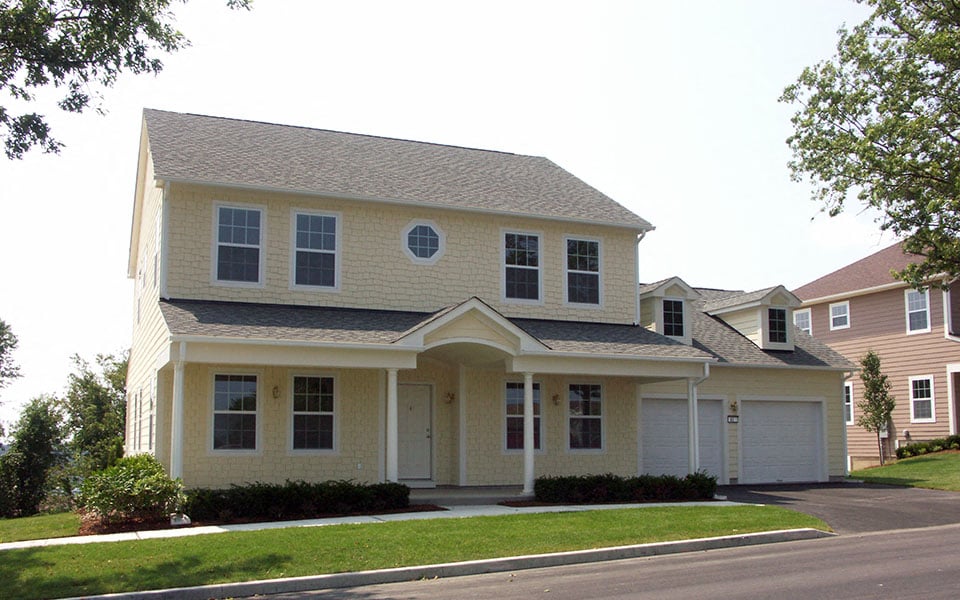 a yellow house with a garage on a street