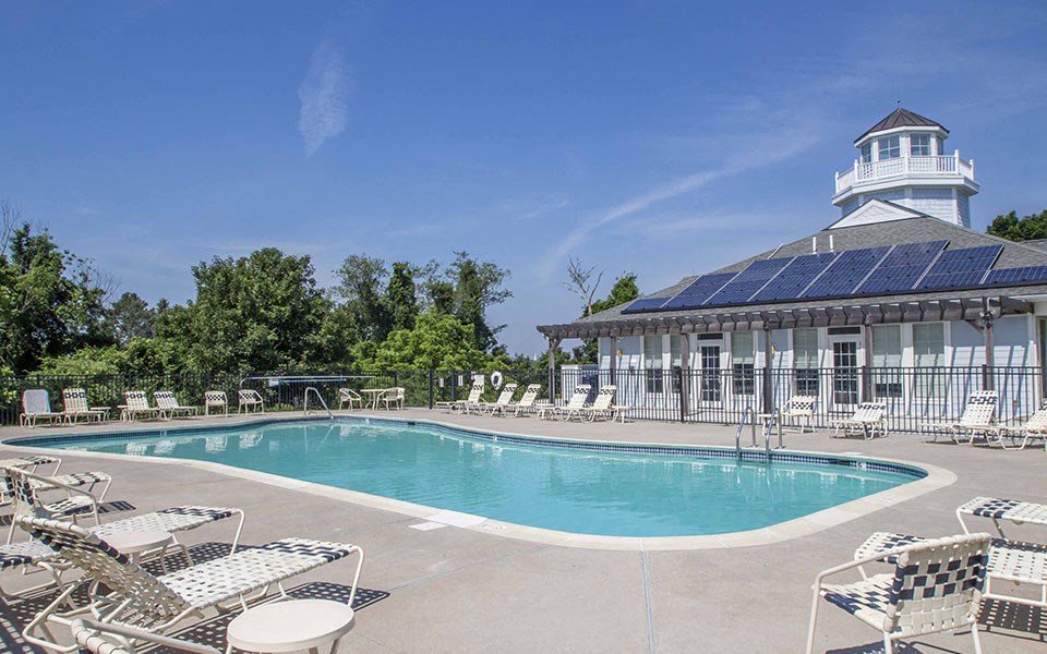 a swimming pool with chairs around it and a white building with a tower