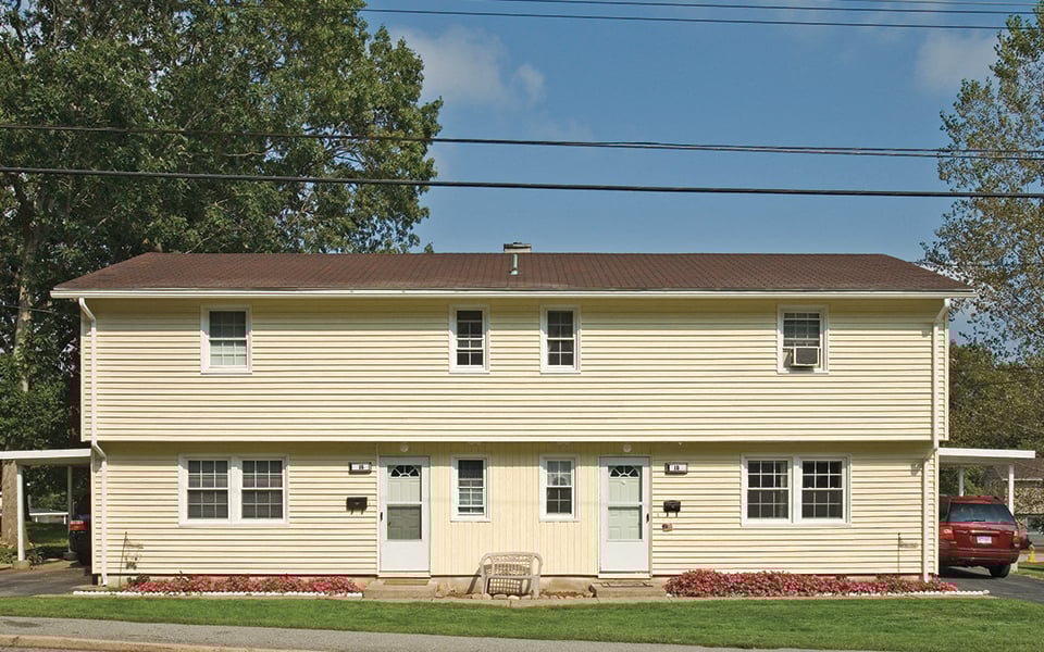 the front of a yellow house with green doors and a lawn