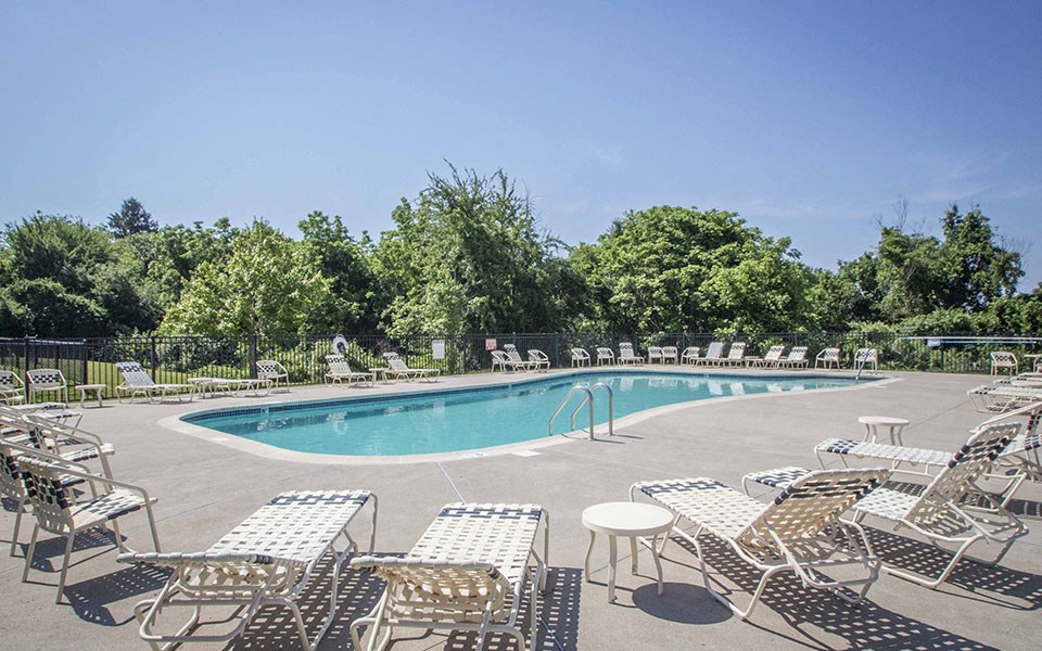 a swimming pool with chairs and tables around it