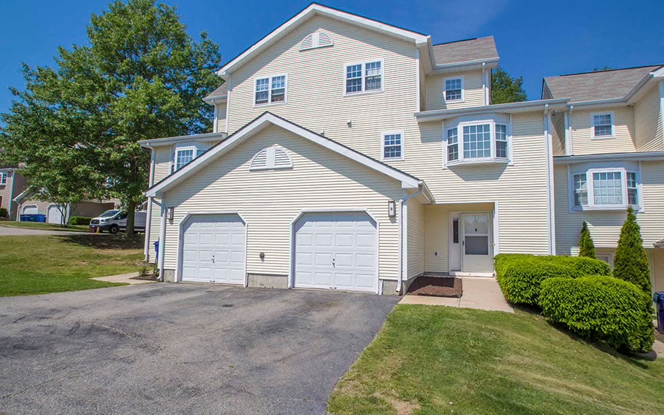 a white house with two garage doors on a driveway
