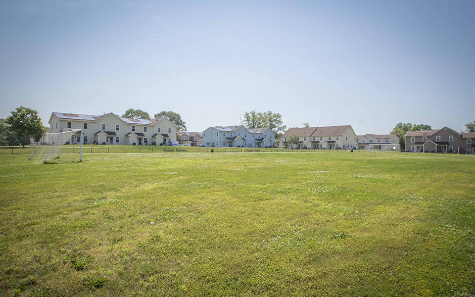 a soccer field with houses in the background