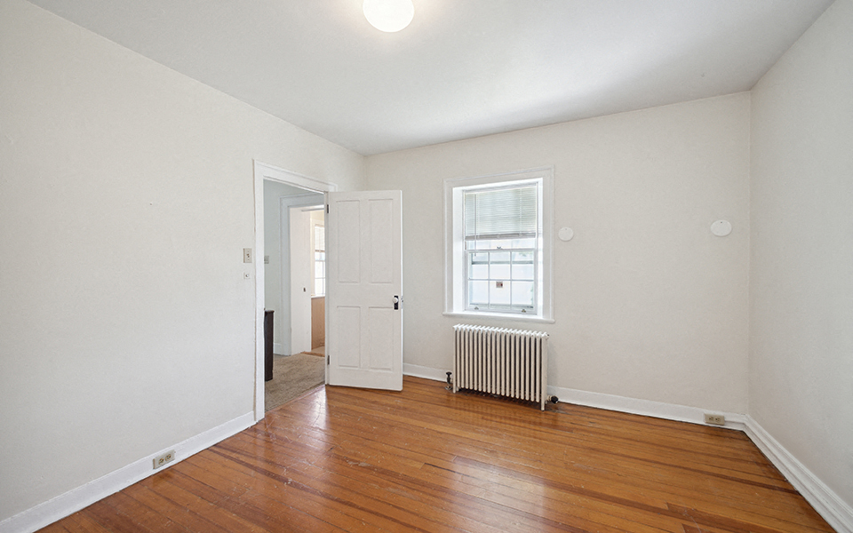 a living room with wood flooring and a door to a hallway