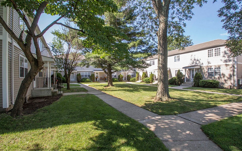 a sidewalk in front of a house with trees