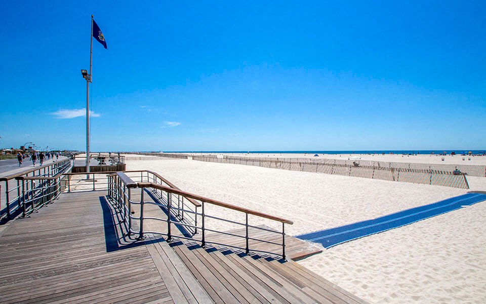 a beach with a wooden boardwalk and a flag