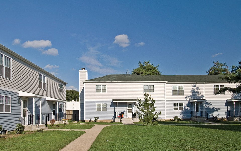 a row of houses with a grass yard and a sidewalk