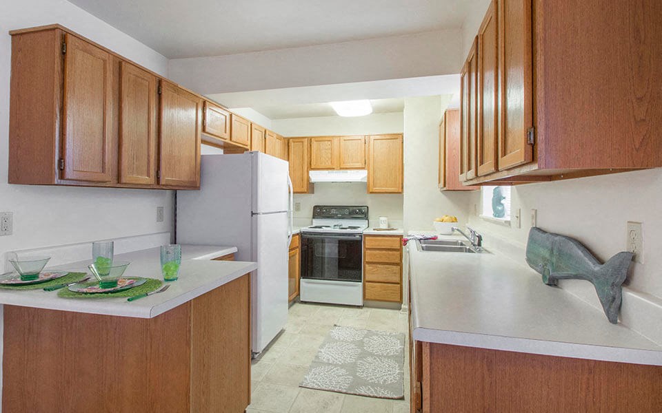 MitchelManor a kitchen with white appliances and wooden cabinets