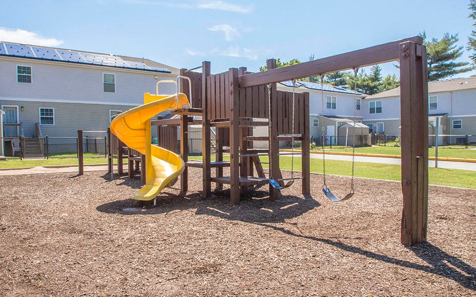 a playground with a slide and swings in a park