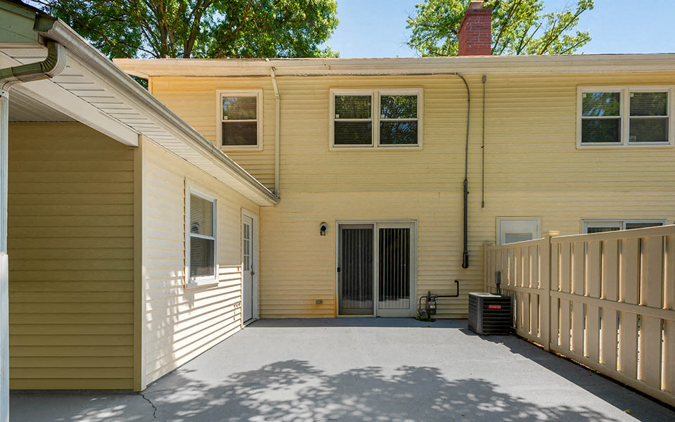 the front of a yellow house with a large driveway