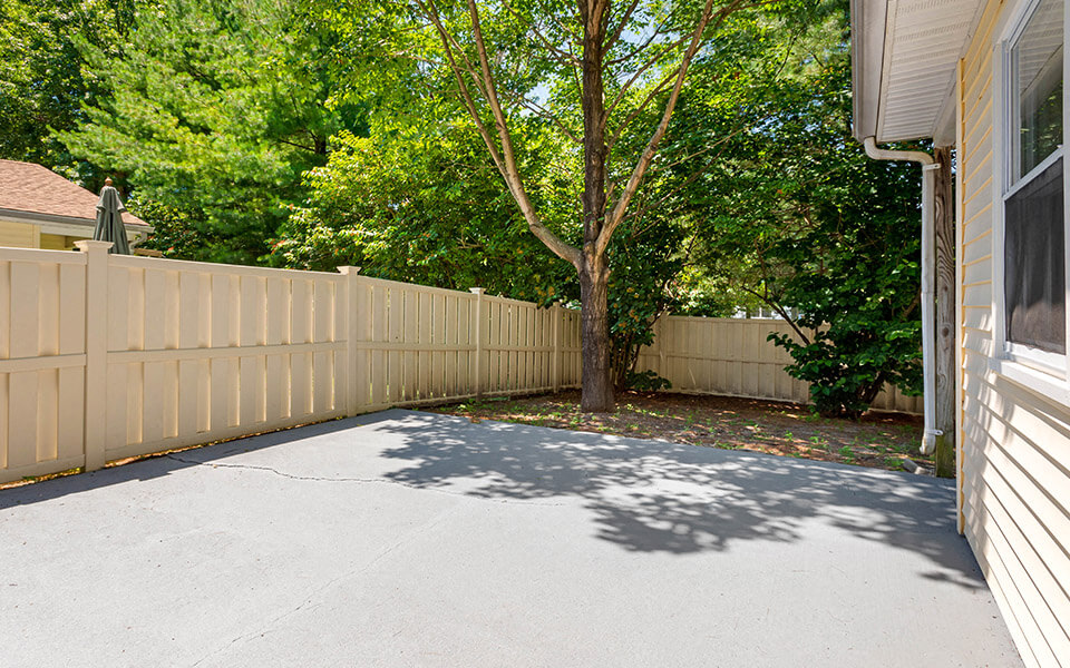 a yard with a fence and a tree in front of a house