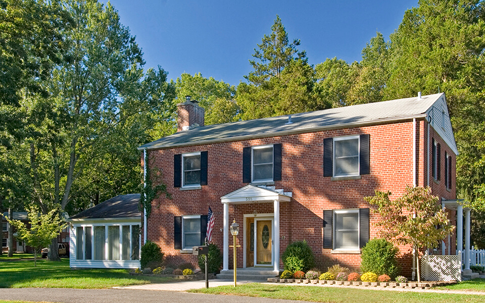 a red brick house with a green lawn and trees