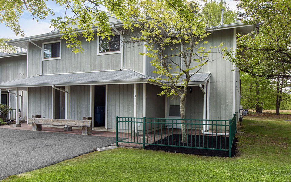a white house with a porch and a tree