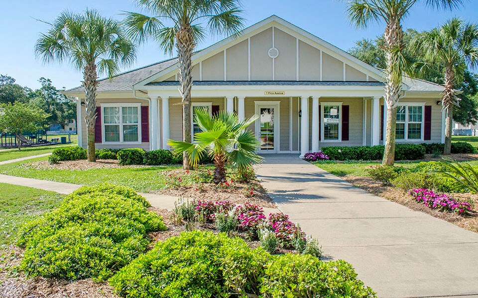 a house with palm trees and a sidewalk in front of it