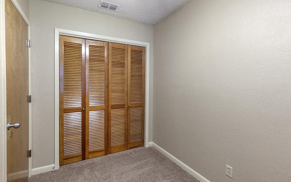 an empty room with two wooden closet doors