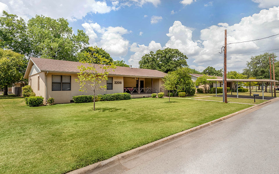 a house with a lawn and a road in front of it