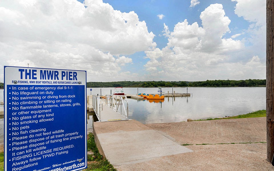 a sign for the mnr pier on the lake with boats in the water