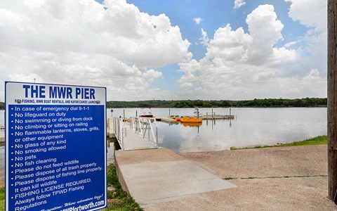 a sign for the mnr pier on the lake with boats in the water