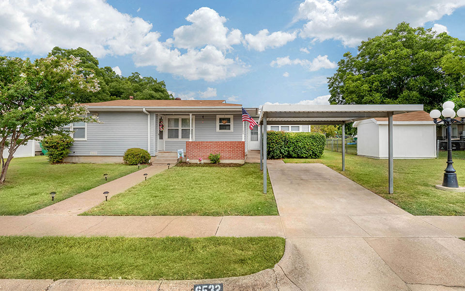 a small blue house with a lawn and a driveway