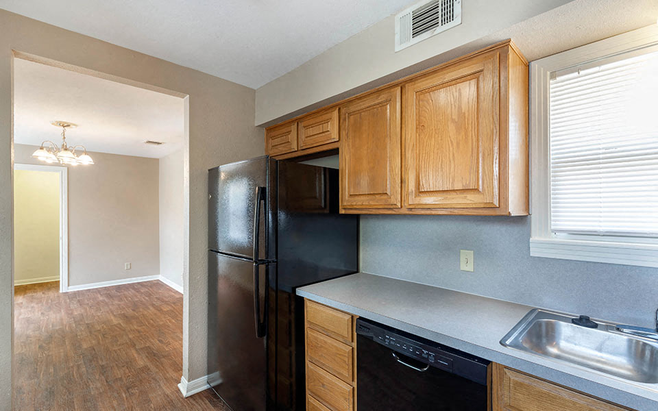 a kitchen with a black refrigerator and wooden cabinets