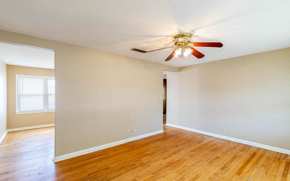 an empty living room with a ceiling fan and wood floors