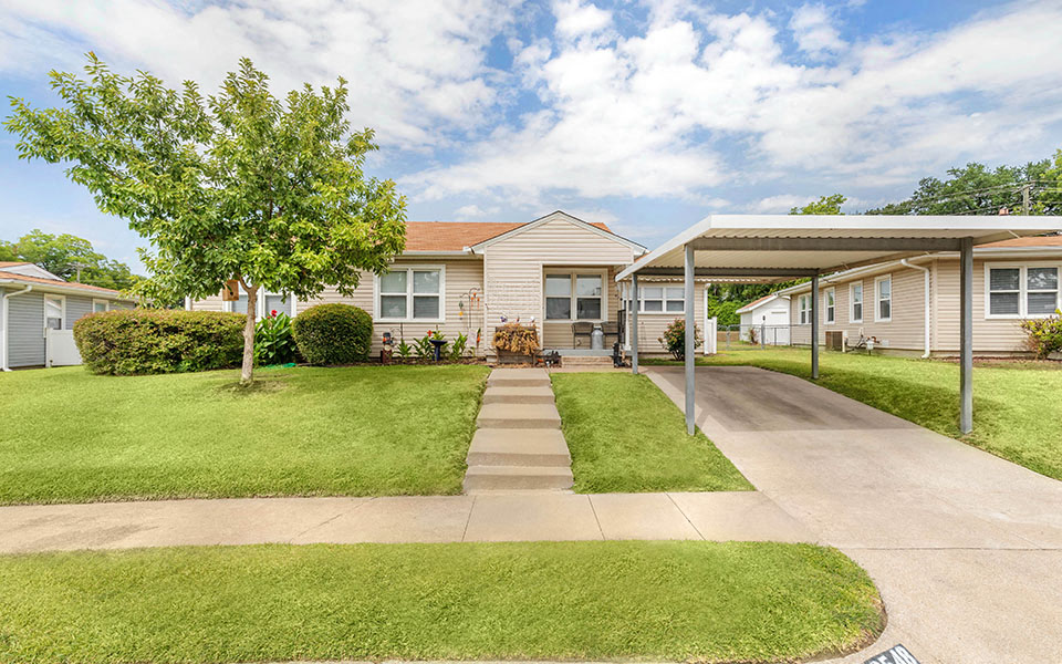 a house with a sidewalk and a tree in front of it