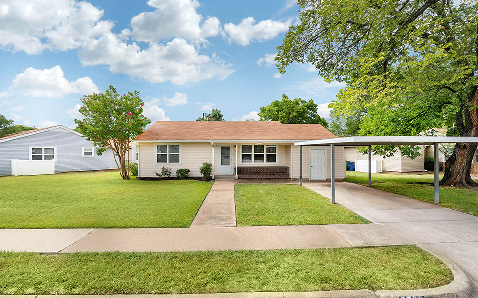 a small white house with a lawn and a driveway