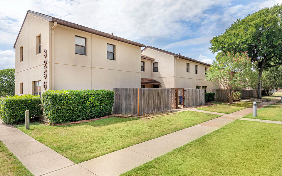 the outlook of an apartment building with a sidewalk and grass