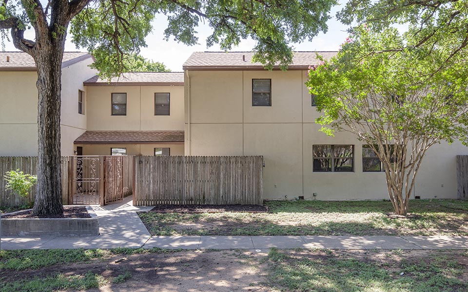 a house with a fence and a tree in front of it