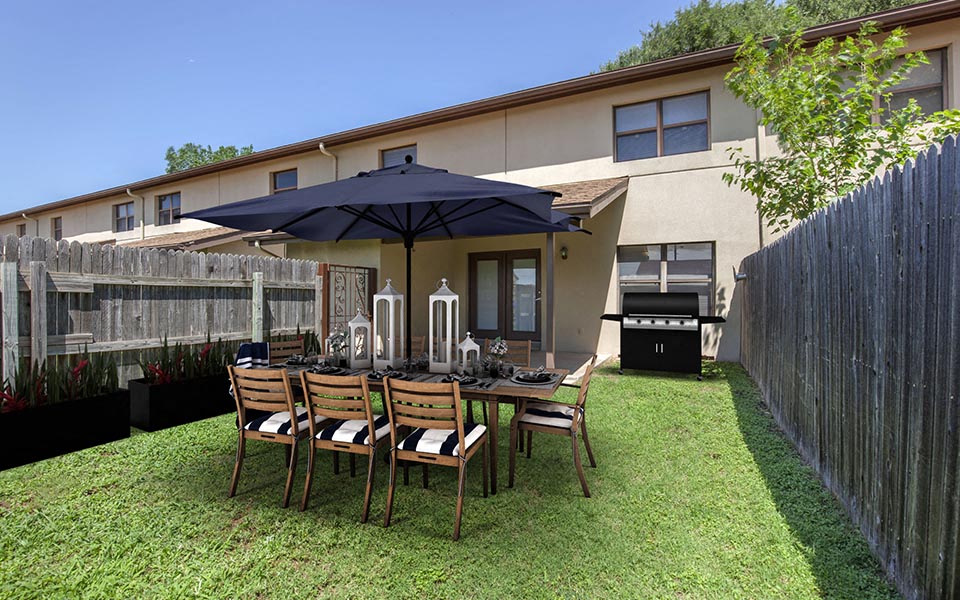 a table and chairs in a backyard with an umbrella