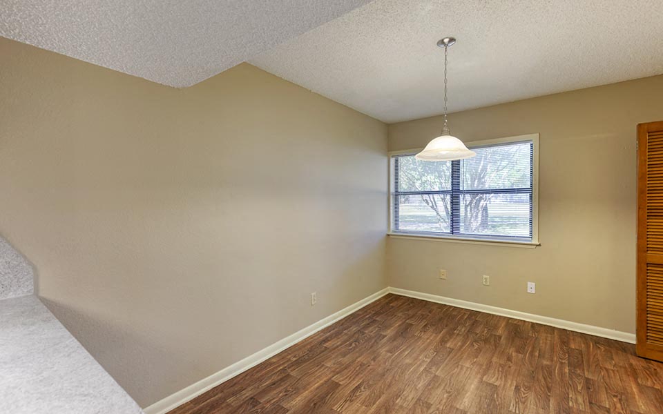 an empty living room with wood floors and a window