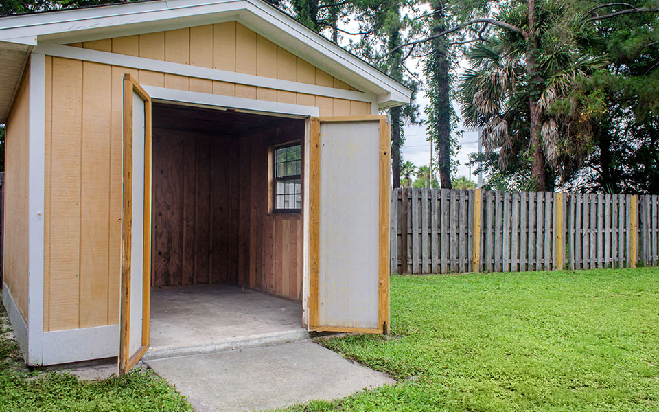 a small shed in a yard next to a fence