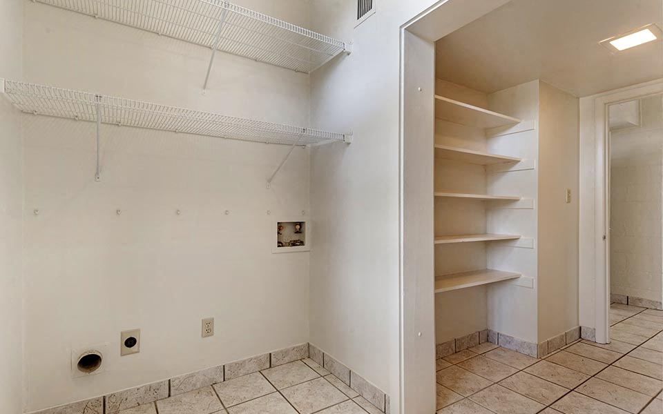 an empty bathroom with a closet and empty shelves