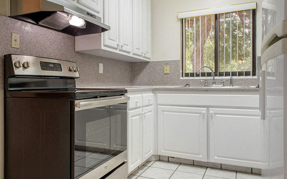 a kitchen with white cabinets and a stove and a window