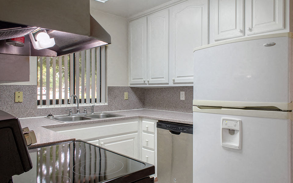 a kitchen with white cabinets and a sink and a refrigerator